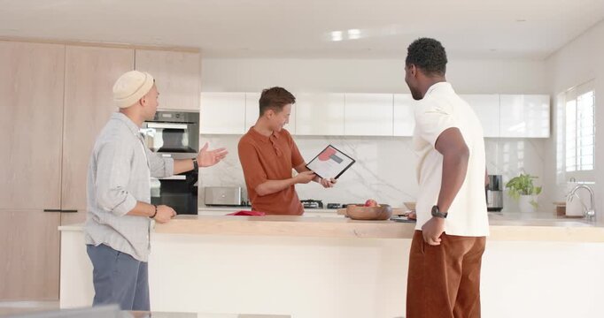 Diverse male friends at kitchen island, Asian man rotating tablet to show content and explain