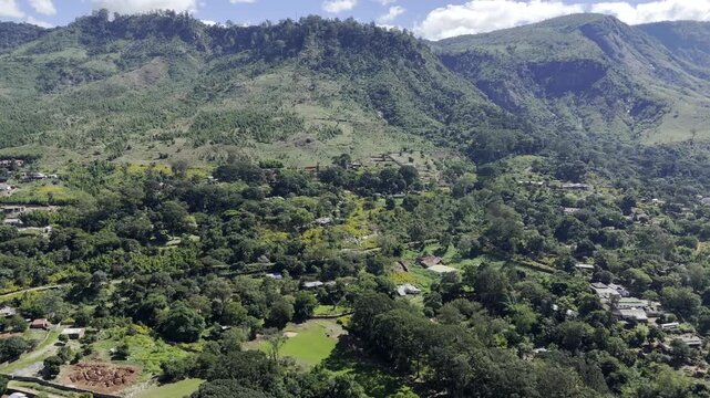 Drone flies toward forest in middle of Zomba Plateau on a sunny day in Zomba, Malawi