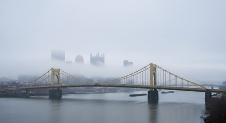Fototapeta premium Pittsburgh skyline and yellow suspension bridge shrouded in thick fog