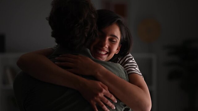 Young happy woman running to her beloved man for a warm, heartfelt embrace in a dimly lit room, showing love and reunion