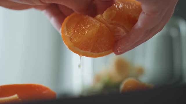 Closeup hands peeling orange segment in soft morning light, home cook preparing breakfast, textured citrus pulp glistening with juice, gentle slow movement over countertop, warm natural tones