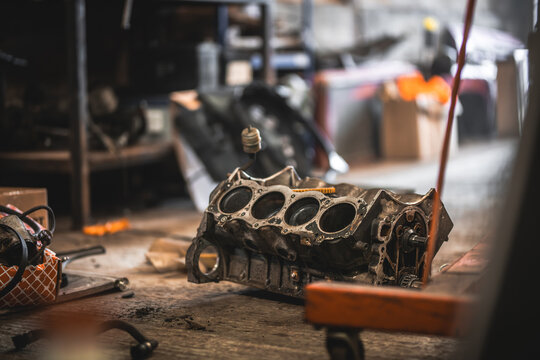 Automotive v8 engine block resting on a dirty garage floor with tools nearby