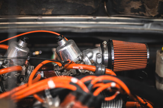Close-up of a vintage car engine with twin carburetors and orange air filter