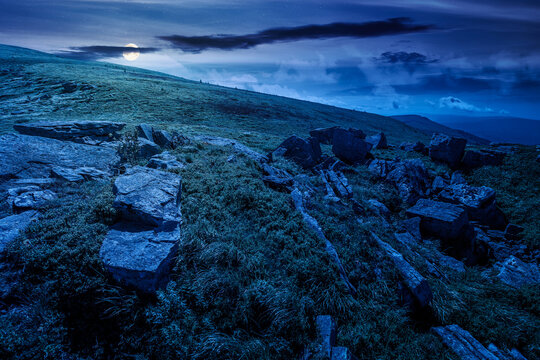alpine grassy meadow at night. full moon over carpathian mountains landscape with huge boulders. alpine nature scenery of ukraine highlands in summer. mysterious view of remote place in mountains