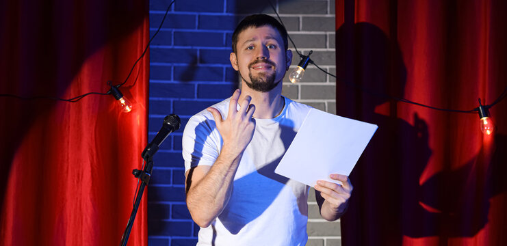 Male actor with film script acting on stage during audition