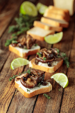 Sandwiches with baked mushrooms on an old wooden table.