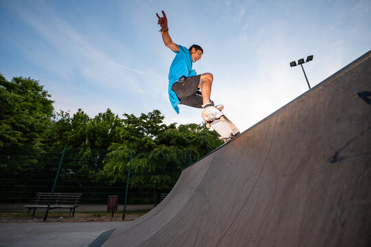 Skateboarder performing trick on half-pipe in skatepark