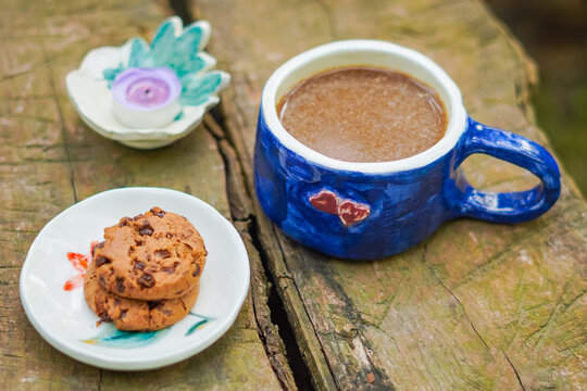 scena still life con una tazza, una candela, e un piattino con biscotti sul tavolo all'aperto;