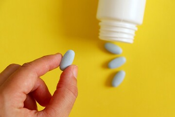 Fototapeta premium Woman holding medicine pill with white bottle medicine in a yellow background. 