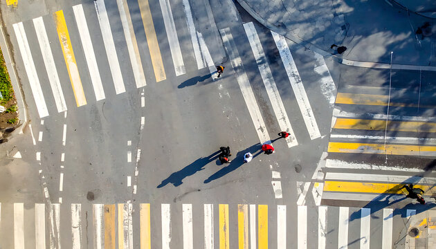 Aerial view of a pedestrian crossing with people walking across the street, urban intersection, crosswalk safety, transportation concept