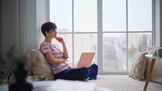 Inspired writer thinking ideas holding laptop on knees sitting floor living room