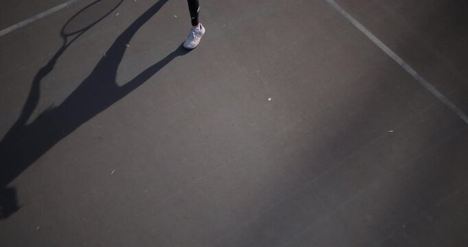 A young girl intensely focused on a tennis game, hitting a forehand on a sunlit outdoor court. This image captures the essence of youth sports and dedication.
