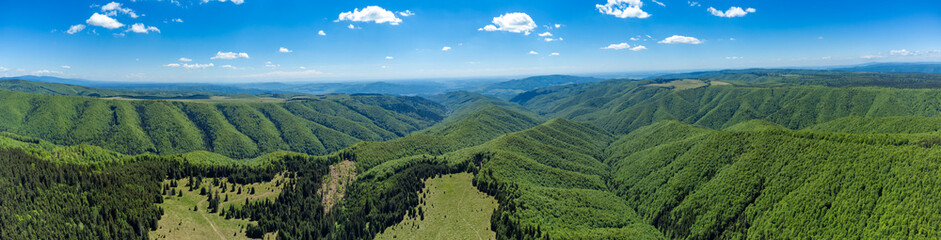 Obraz premium Stunning aerial perspective of the Gurghiu-Harghita Mountains of Transylvania, Romania highlights dense rolling green deciduous and coniferous forests blanketed across deep mountain valleys and ridges