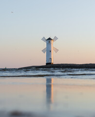 Fototapeta premium Stawa Młyny in Świnoujście in Polen zur Morgendämmerung mit goldenem Morgenlicht auf der Mühle, ruhiger Ostsee und Spiegelung im stillen Wasser