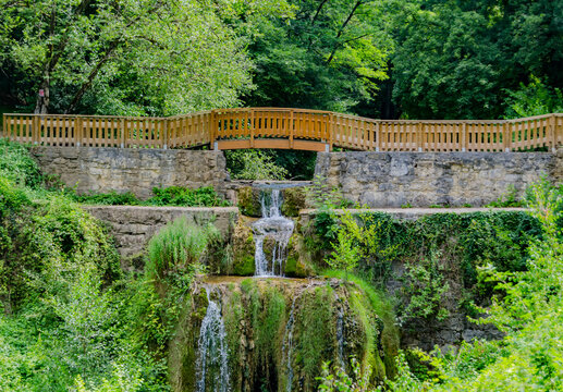 &laquo; Cascade am&eacute;nag&eacute;e sous une passerelle en bois dans un d&eacute;cor naturel luxuriant &raquo;
