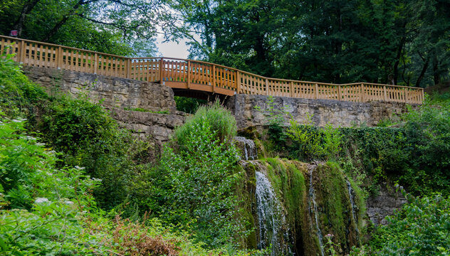 &laquo; Cascade discr&egrave;te sous une passerelle en bois au c&oelig;ur d&rsquo;une nature luxuriante &raquo;
