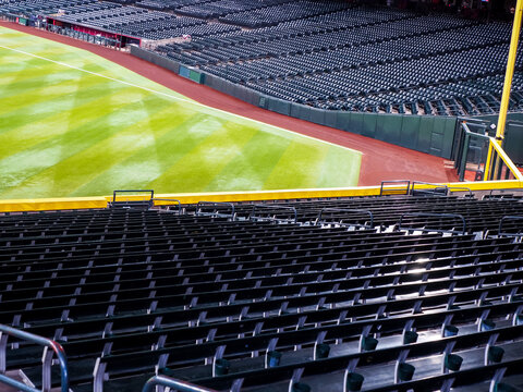 Empty green bleacher seats in left field of a baseball stadium, groomed green grass
