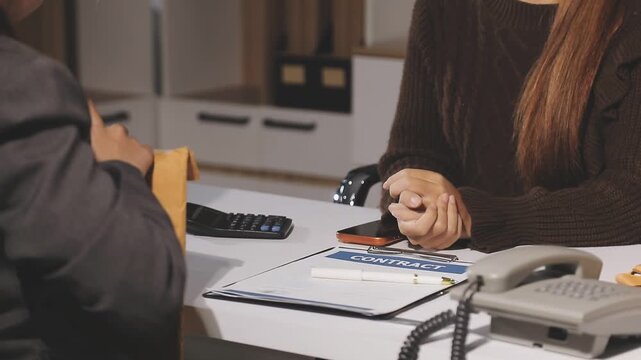 Female attendant handed over the rental car key to the customer who signed the contract and the terms of the agreement on the document, Car rental service concept.