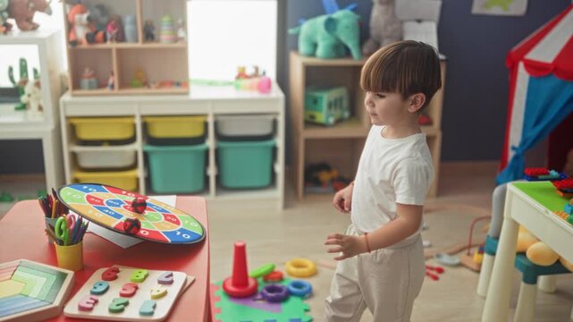 Boy from back playing with toys and wooden train track, reaching toward shelf in building; curiosity childhood.