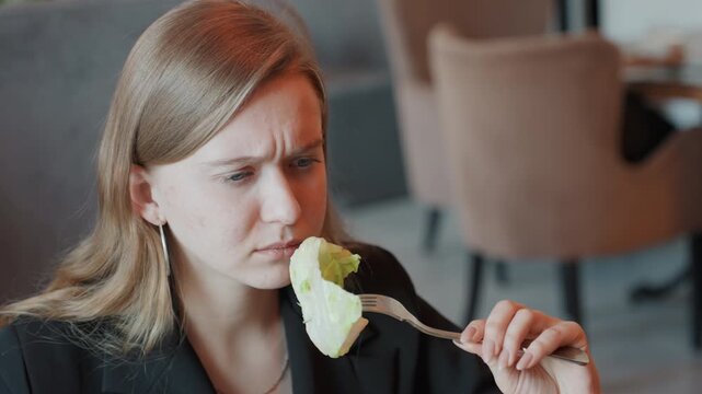 Food critic examines lettuce. Critical culinary analyst focuses intently on crisp lettuce piece. Cuisine evaluator deeply examines fresh lettuce on fork with serious expression and doubt