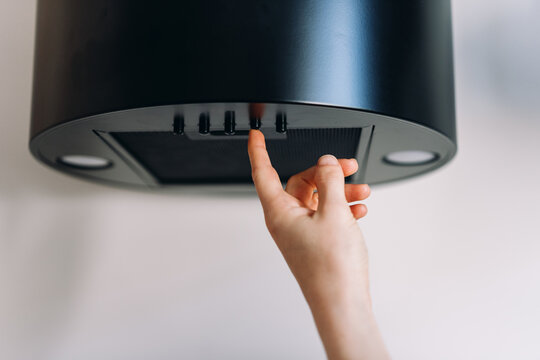 Woman press button on kitchen extractor hood control panel