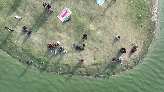 A top panning drone shot captures people enjoying the serene beauty of Deepor Beel, showcasing its natural charm, lush greenery, and peaceful ambiance in a captivating visual.4k