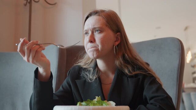 Woman tasting salad makes disgusted face, executive persona reacting to bitter flavor with furrowed brow, fork held midair, pushing plate away, tense lunch break, candid restaurant closeup, emotive