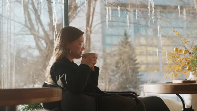 White woman sipping coffee by window, writer soaking golden light, yellow bouquet on table, reflective profile, slow ritual and cozy urban view, gentle bokeh and skyline background