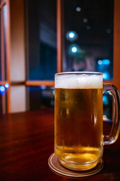 Close up shot of a cold mug of draft beer with bubbles on a wooden table for bar menu.