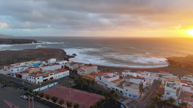 Scenic aerial capture of sunset casting amber hue on choppy ocean waves and rocky formations