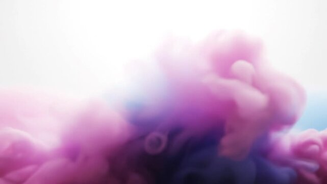 Abstract pink and blue ink clouds swirling in clear liquid against a solid white background, creating fluid smoke-like patterns and colorful plumes of paint in slow motion macro.