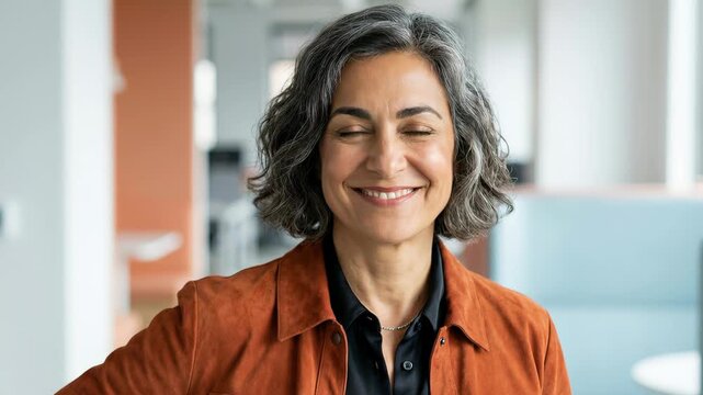 Portrait of a successful senior businesswoman with grey hair smiling while looking at the camera. Beautiful mature professional manager standing in a modern office with a positive attitude