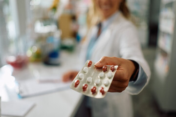 Close up of pharmacist with medicine package in drugstore.