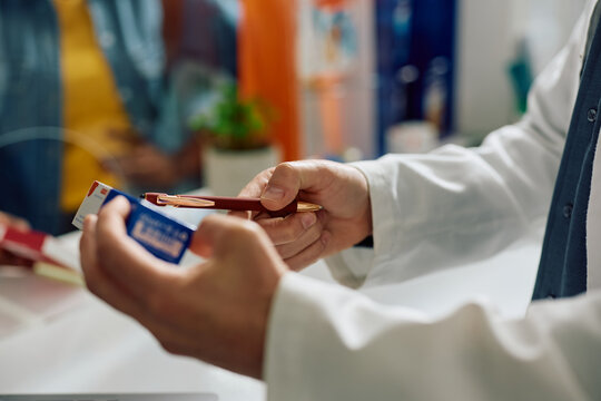 Close up of pharmacist advising customer in taking medicine while working in pharmacy.