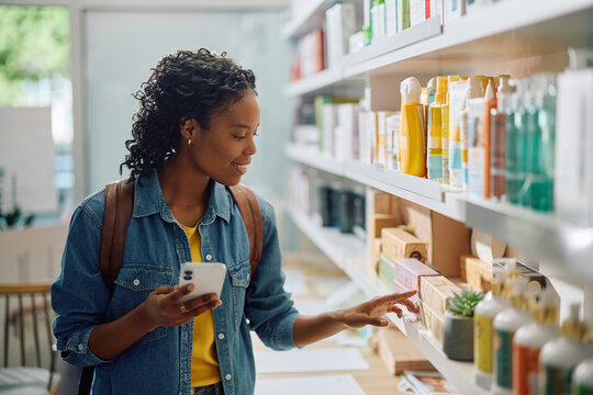 Smiling black woman buying body care products in pharmacy.