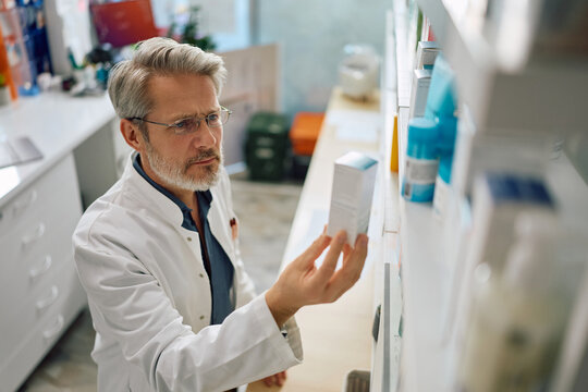 Mature pharmacist going through inventory in drugstore.