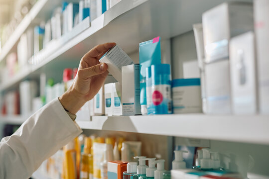 Close up of pharmacist taking medicine box from shelf.
