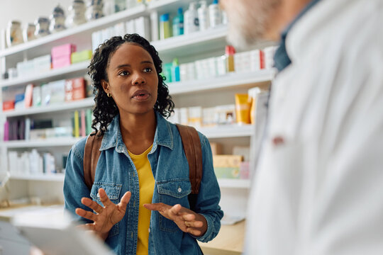Young black woman talking to her pharmacist in pharmacy.
