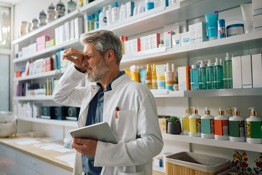 Mature pharmacist having a headache while working in pharmacy.