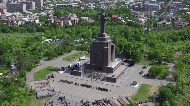 Aerial view of the Mother Armenia monument in Yerevan, featuring a military ceremony at the base of this giant statue on a bright sunny day in late spring.


