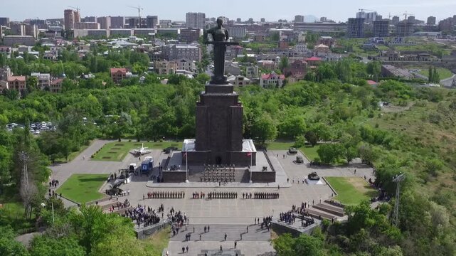 Aerial view of the Mother Armenia monument in Yerevan, featuring a military ceremony at the base of this giant statue on a bright sunny day in late spring.

