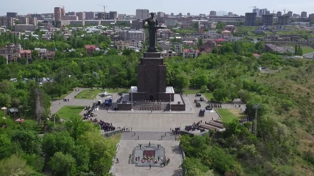 Aerial view of the Mother Armenia monument in Yerevan, featuring a military ceremony at the base of this giant statue on a bright sunny day in late spring.

