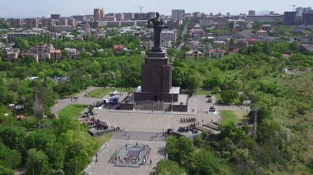Aerial view of the Mother Armenia monument in Yerevan, featuring a military ceremony at the base of this giant statue on a bright sunny day in late spring.

