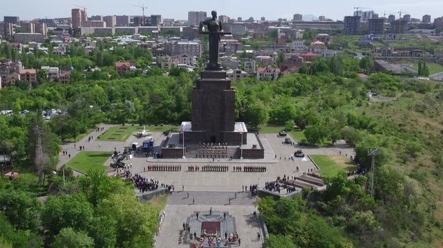 Aerial view of the Mother Armenia monument in Yerevan, featuring a military ceremony at the base of this giant statue on a bright sunny day in late spring.


