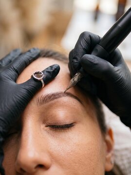 Professional permanent makeup eyebrow tattooing procedure in beauty salon