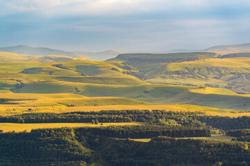 Fototapeta premium Layers of green mountains and hills in the haze during sunset. Panoramic View of Green hills and Meadow.