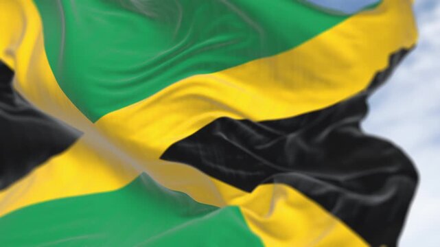 Close-up of Jamaica national flag waving. Gold saltire dividing it into four sections: two green and two black. Seamless 3d render animation. Slow motion loop. Selective focus