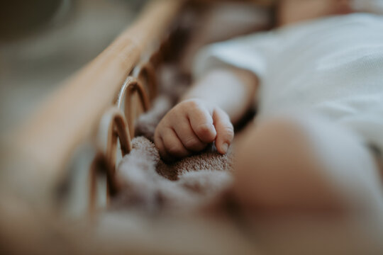 Main de b&eacute;b&eacute; dans un berceau en bois