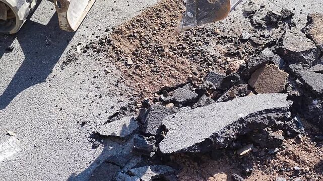 Excavator bucket breaking and crushing concrete slab at outdoor demolition site
