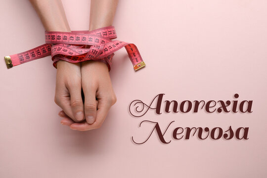 Anorexia concept. Woman tied with measuring tape on pink background, top view